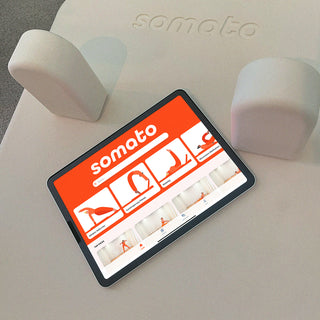 Tablet displaying the Somato app home screen, resting on the Somato Reformer carriage.