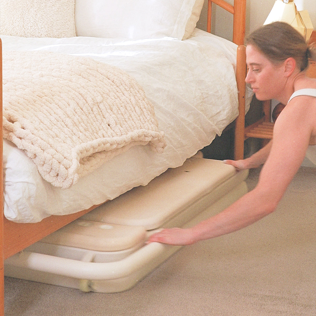 Foldable Pilates Reformer being stored under a bed, demonstrating easy home storage.