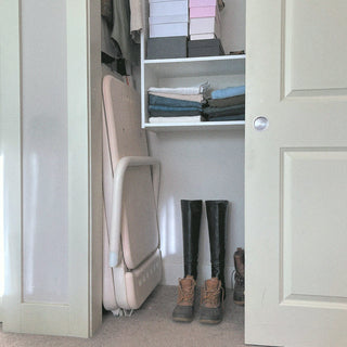 Folded Pilates Reformer stored upright in a closet, showcasing its space-saving, compact design.